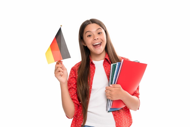 Überraschtes Kind hält deutsche Flagge und Schulheft für das Lernen isoliert auf weißer deutscher Sprache