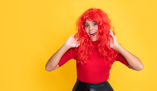 Überraschtes Kind mit roten langen Haaren auf gelbem Hintergrund