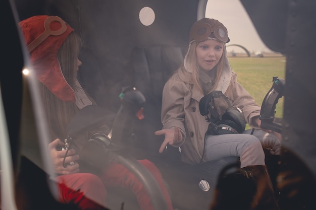 Überraschtes Tween-Mädchen, das mit Freund auf dem Pilotensitz im Hubschraubercockpit sitzt