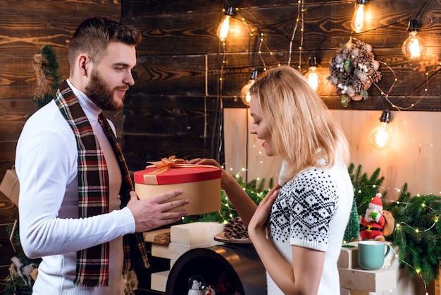 Überraschung für Schatz. Frohe Weihnachten und ein glückliches Neues Jahr. Weihnachtsgeschenke. Mann schön mit Geschenkbox Überraschung für Freundin. Mann Hipster geben Mädchen Weihnachtsdekorationen Geschenk.