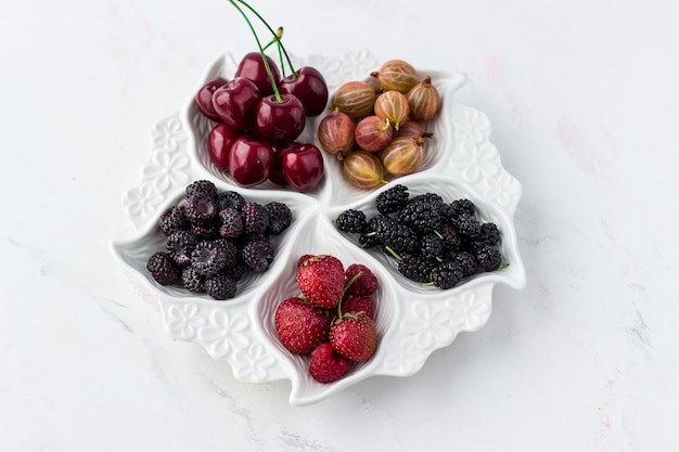 Berry Platte auf weißem Hintergrund Erdbeeren Stachelbeeren Kirschen Himbeeren und Maulbeeren