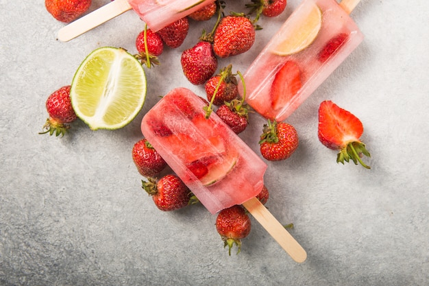 Berry Popsicle com varas de madeira no balcão de concreto. Barras de frutas congeladas de morango caseiro