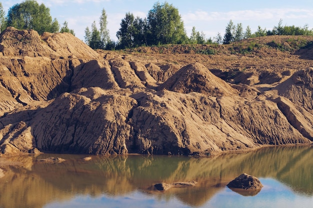 Überschwemmter Sandsteinbruch Gebrochene Dürre-Tonhaufen während der Trockenzeit Leuchtend gelbe oder orangefarbene Textur Sandfarbe Land Stock-Hintergrundfoto Sychevo-Minen Wolokolamsk-Bezirk der Region Moskau