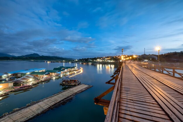 Berühmte hölzerne mon-brücke mit traditionellem dorf in sangkhlaburi in der dämmerung kanchanaburi thailand