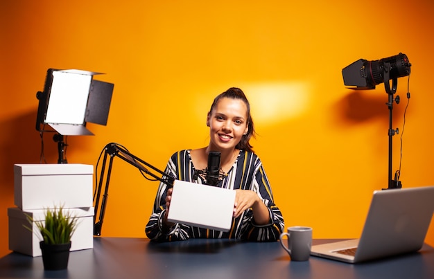 Berühmte kreative Frau beim Aufnehmen von Werbegeschenken aus dem Heimstudio