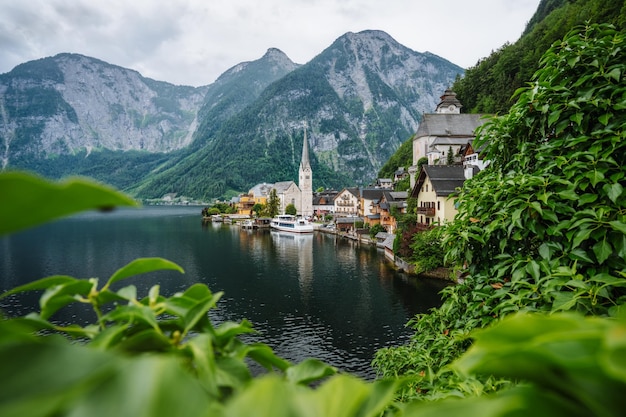 Berühmte Seeseitenansicht des Dorfes Hallstatt mit Alpen hinter Laubblättern umrahmt Österreich