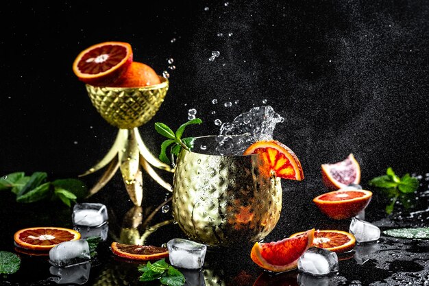 Berühmter Moscow Mule alkoholischer Cocktail in Kupferbecher mit Blutorangen-Ingwer-Bier-Wodka und Minze spritzt gefrorene Bewegung