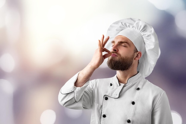 Berufskochmann, der Zeichen für köstliches zeigt. Männlicher Koch in weißer Uniform mit perfektem Zeichen.