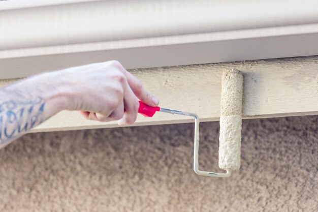 Berufsmaler mit einer kleinen Walze, um die Fascia des Hauses zu malen