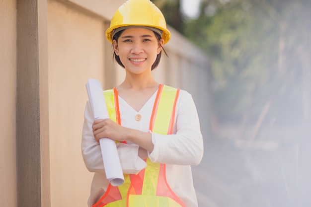 Berufstätige Frauen, die Blaupausenpapierdokument halten, das am Hochbau steht, Sie ist Vorarbeiter-Kontrollprojekt