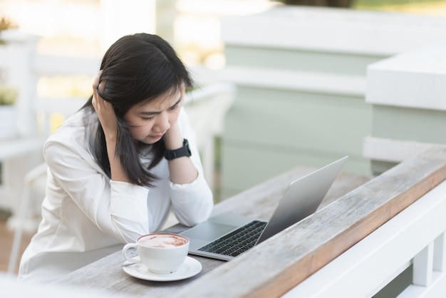 Berufstätige Frauen, die hart mit Laptop im Café denken und arbeiten