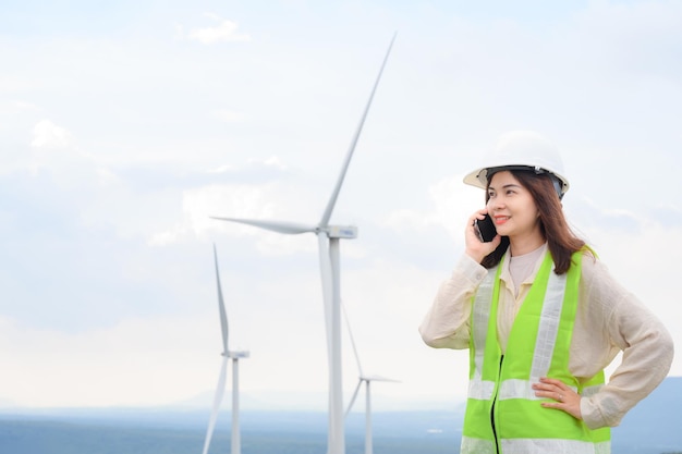 Berufstätige Ingenieurin Inspektion von Windkraftanlagen und Windkraftanlagen-Inspektionsfortschritt an einer erneuerbaren Stromerzeugungsstation Erörterung der Arbeit am Telefon