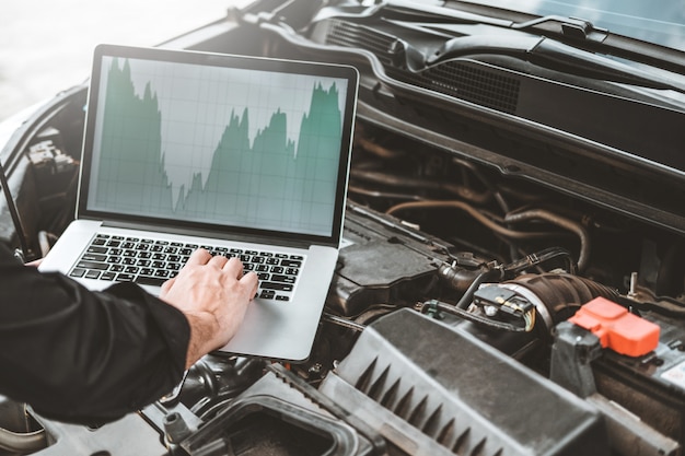 Berufstechniker hands der prüfung des automotor-reparaturdienstes unter verwendung des laptops auf auto
