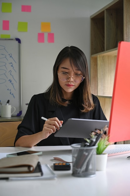 Überzeugte Geschäftsfrau, die mit digitaler Tablette arbeitet.