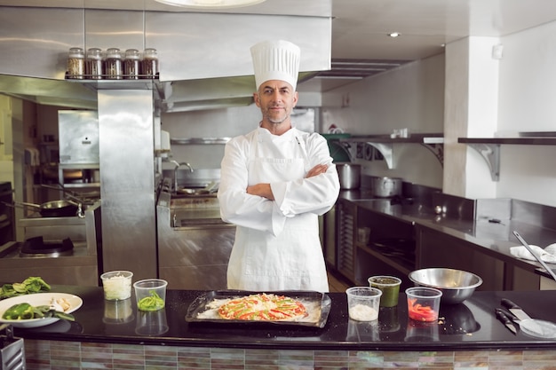 Überzeugter männlicher Chef mit gekochtem Essen in der Küche