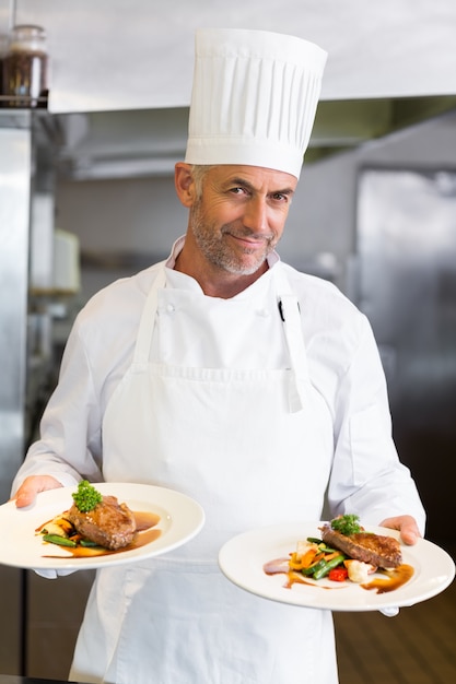 Überzeugter männlicher Chef mit gekochtem Essen in der Küche