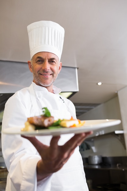 Überzeugter männlicher Chef mit gekochtem Essen in der Küche