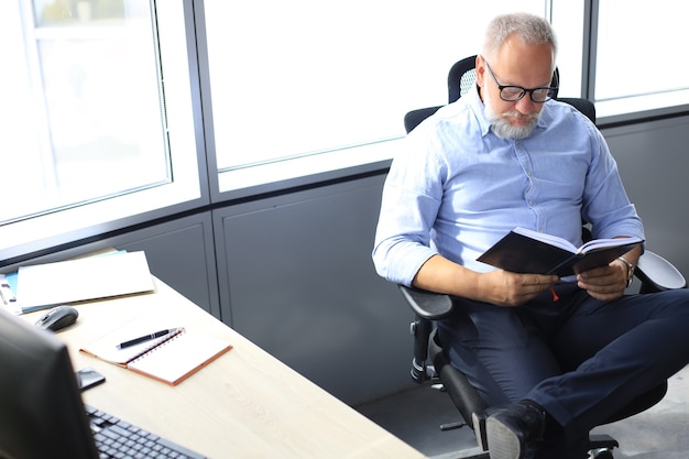 Überzeugter nachdenklicher reifer Geschäftsmann im modernen Büro.