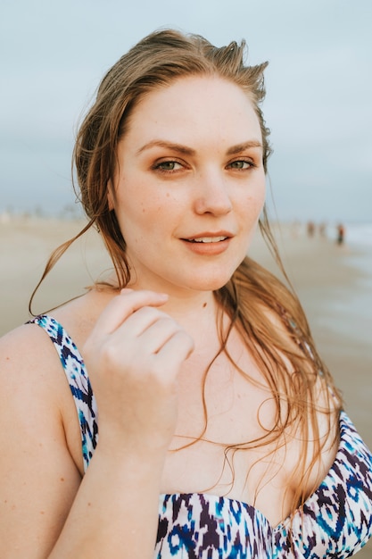 Überzeugtes blondes plus Größenfrau am Strand