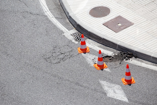 Beschädigte Stadtstraße, die mit Kegeln markiert ist, die auf Reparatur warten