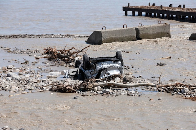 Beschädigtes Auto am Meeresufer nach einer Naturkatastrophe spülte ein Gebirgsfluss das Auto ins Meer