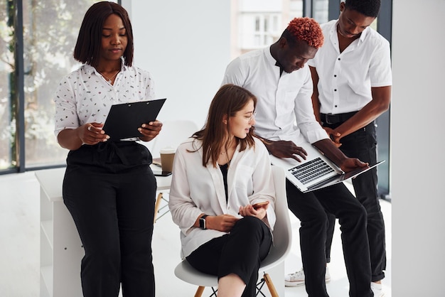 Beschäftigt und halten Laptop und Notizblock Gruppe afroamerikanischer Geschäftsleute, die gemeinsam im Büro arbeiten