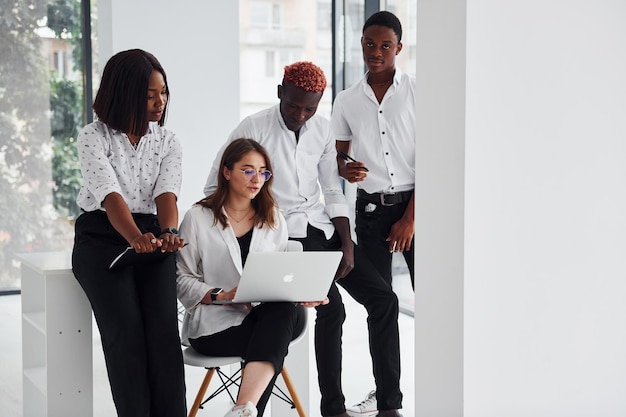 Beschäftigt und halten Laptop und Notizblock Gruppe afroamerikanischer Geschäftsleute, die gemeinsam im Büro arbeiten