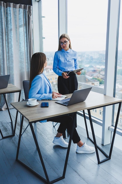 Beschäftigte Geschäftsfrauen mit einem Laptop im Büro, die sich Inhalte auf dem Laptop ansehen und das Projekt gemeinsam besprechen, während sie während einer Arbeitspause im Büro sitzen Teamwork-Unternehmensdiskussion