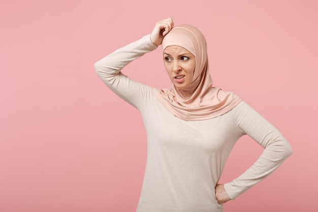 Beschäftigte junge arabische Muslimin in Hijab-leichter Kleidung posiert isoliert auf rosa Hintergrund, Studioportrait. Menschen religiösen Islam Lifestyle-Konzept. Mock-up-Kopienbereich. Hand auf den Kopf legen.