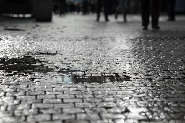 Beschäftigte Stadtleute auf den Straßen der Stadt. Pfütze im Vordergrund. Absichtliche Bewegungsunschärfe