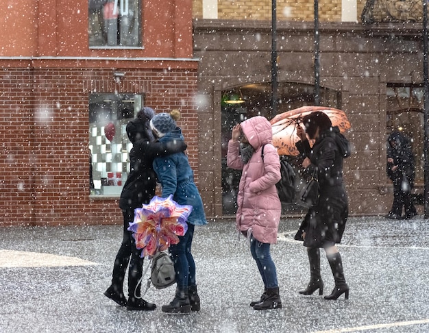 Beschäftigte Stadtleute, die am verschneiten Wintertag die Straße entlang gehen. Absichtliche Bewegungsunschärfe. Unscharfes Bild