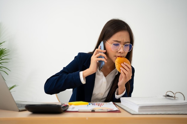 Foto beschäftigte und müde geschäftsfrau isst brot und milch zum mittagessen im schreibtischbüro