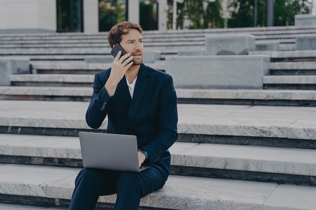 Beschäftigter männlicher Unternehmer, der mit Statistikdaten beschäftigt ist, bespricht die Leistung über das Mobiltelefon