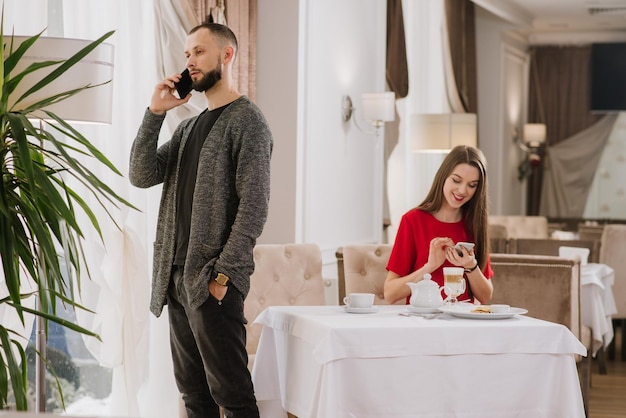 Beschäftigtes Paar, das am Telefon und im Restaurant spricht