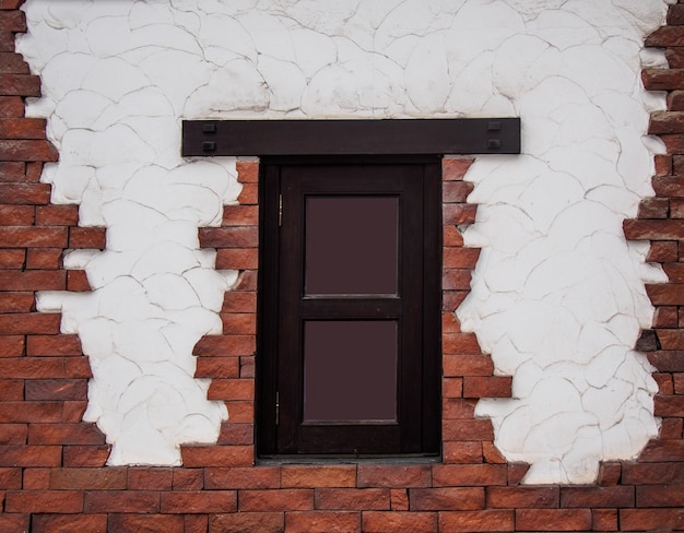 Beschaffenheit des dunkelbraunen Fensterrahmens auf dem Zement und der Backsteinmauer eines Hauses