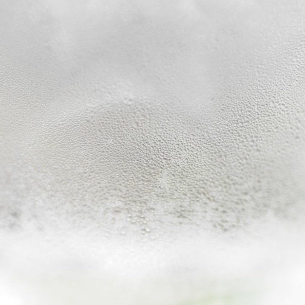 Beschlagenes Glas mit Tropfen Eiswasser in Nahaufnahme. Erfrischendes und kühlendes Getränk bei heißem Wetter