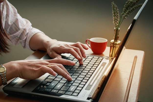 Beschnittene Hände einer Geschäftsfrau mit Laptop auf dem Schreibtisch
