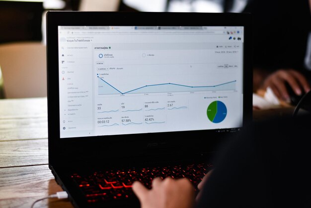 Beschnittene Hände einer Person, die einen Laptop auf dem Tisch benutzt