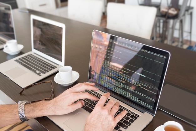 Beschnittene Hände eines Geschäftsmanns, der einen Laptop im Büro benutzt