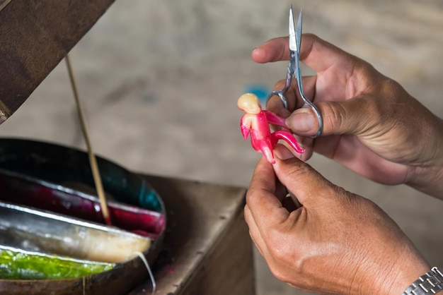 Beschnittene Hände eines Handwerkers, der ein Figurenspielzeug herstellt