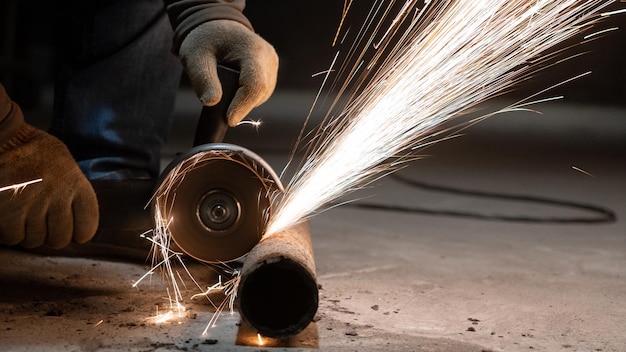 Beschnittene Hände eines Mannes, der Metall in einer Werkstatt schneidet