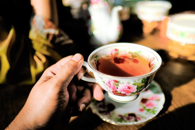 Foto beschnittene hand, die an einem sonnigen tag tee trinkt