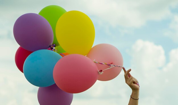 Foto beschnittene hand, die ballons gegen den himmel hält