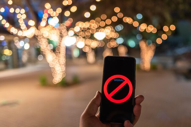 Foto beschnittene hand hält ein handy, während sie nachts auf der straße steht