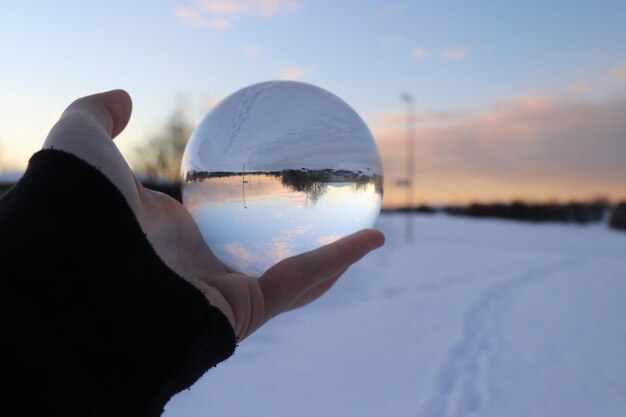 Foto beschnittene hand hält im winter eine kristallkugel