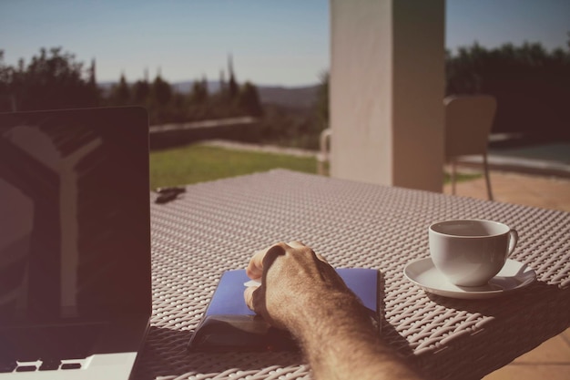 Foto beschnittene hand mit drahtloser maus an der kaffeetasse auf dem tisch