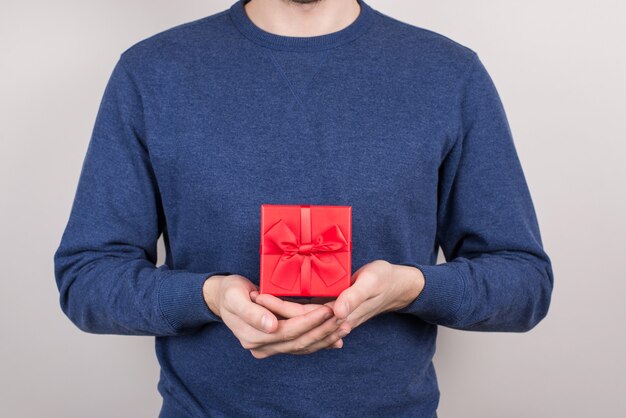 Beschnittene Nahaufnahme fröhlich gut froh froh positive optimistische Person zeigt schönen schönen quadratischen Behälter für teures Geschenk in Palmen isolierte graue Wand