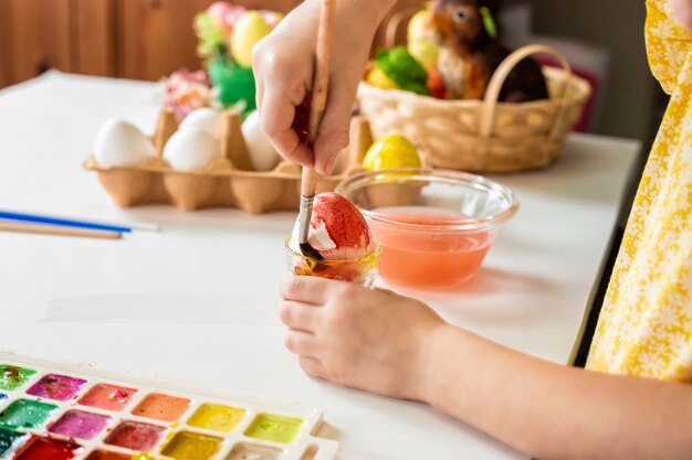 Beschnittener Schuss des entzückenden kleinen Mädchens, das Ei für Ostern malt.