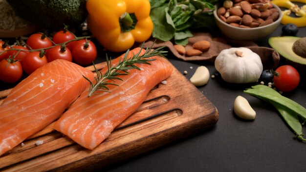 Beschnittener Schuss des gesunden Nahrungsmittelsortiments mit Lachs, Obst, Gemüse, Samen und Kopienraum auf schwarzem Tisch
