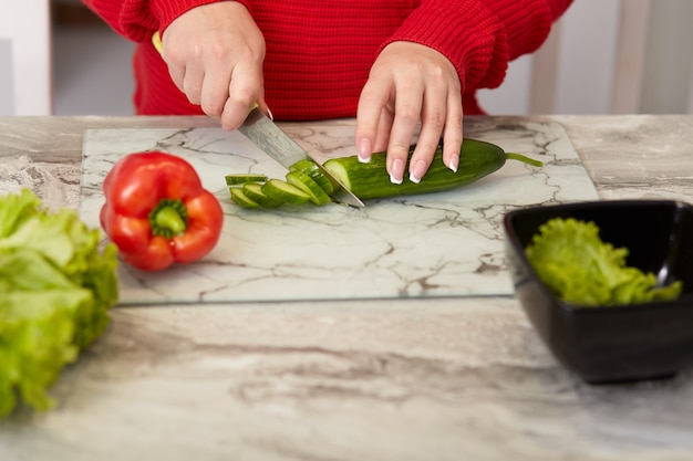 Beschnittenes Bild der Frauenhände schneidet Gemüse mit Messer